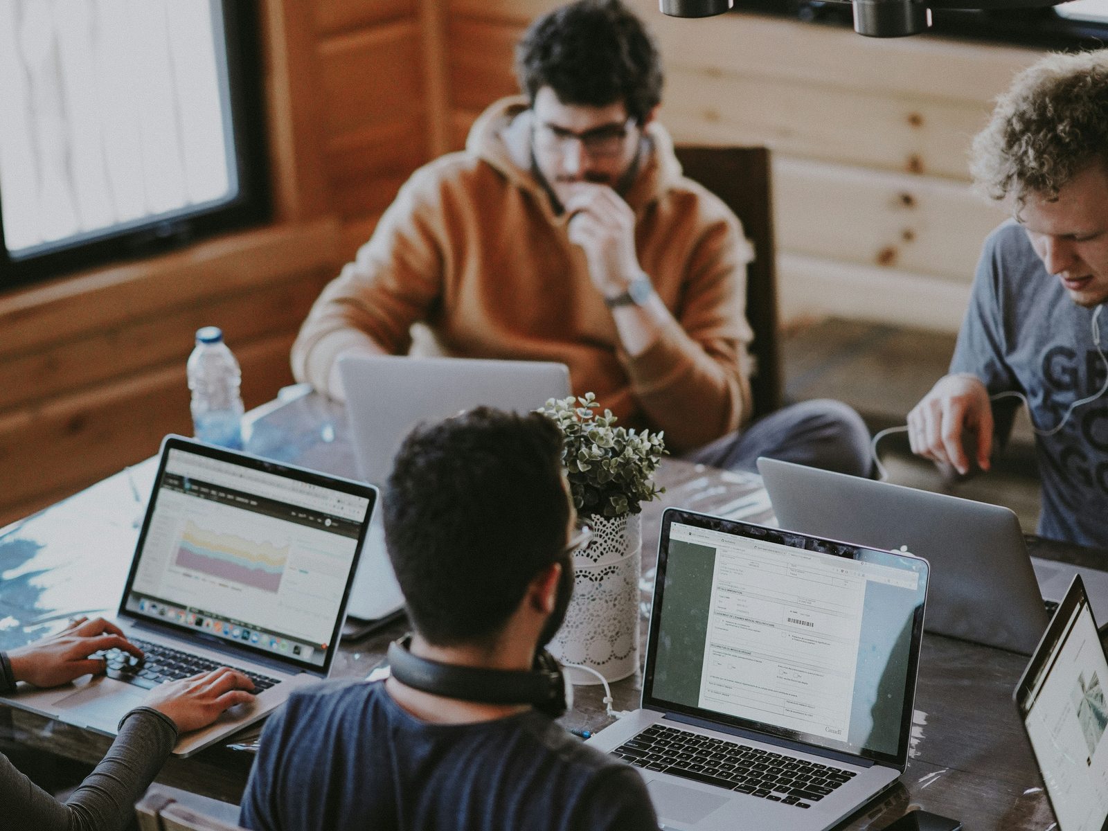 Team members working together on laptops around a wooden table